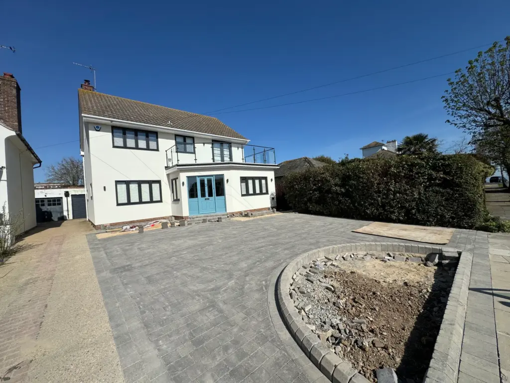 Charcoal block paving laid in full herringbone bond on a new driveway in Frinton-on-Sea, planting bed still to be backfilled