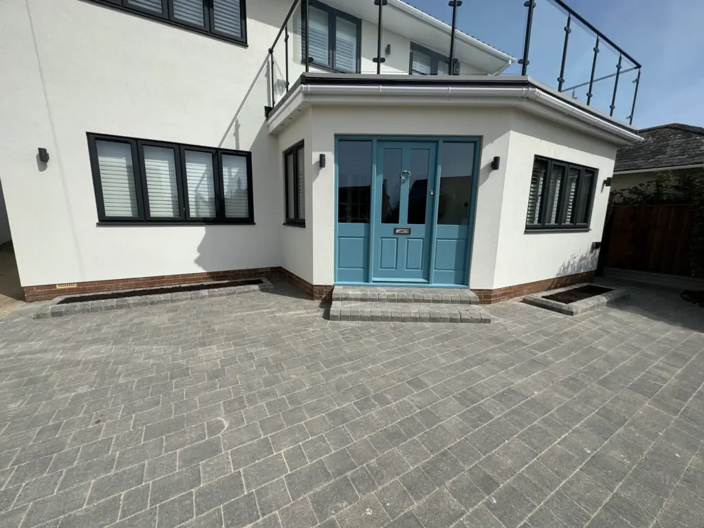 Close-up of the finished driveway entrance in Frinton-on-Sea, showing block paving detail and planting beds either side of the front door