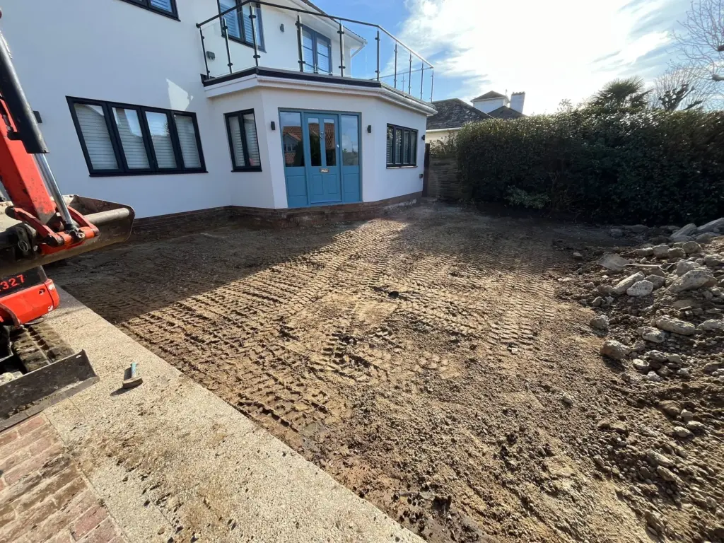 Excavation stage of a driveway installation in Frinton-on-Sea, mini digger stripping back the old paving to sub-grade