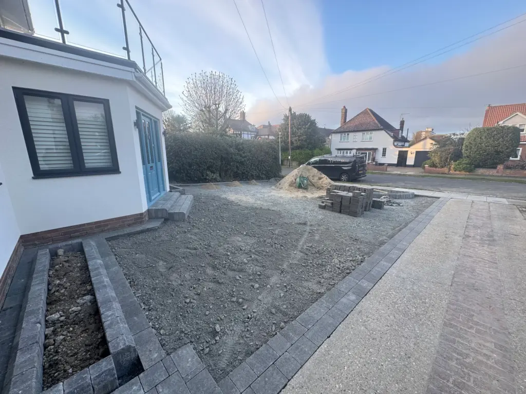 Sub-base preparation close to the house on a Frinton-on-Sea driveway installation, with edging blocks and paving stock staged ready for laying