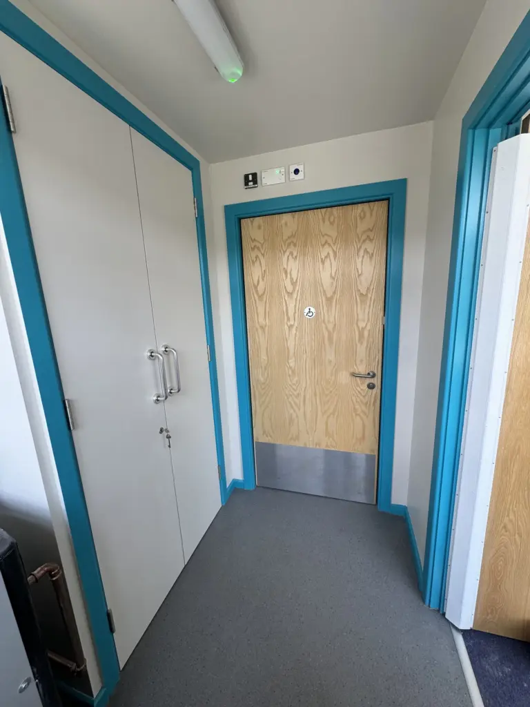Accessible WC doorway with pictogram signage at The Hawthorns School washroom in Chelmsford