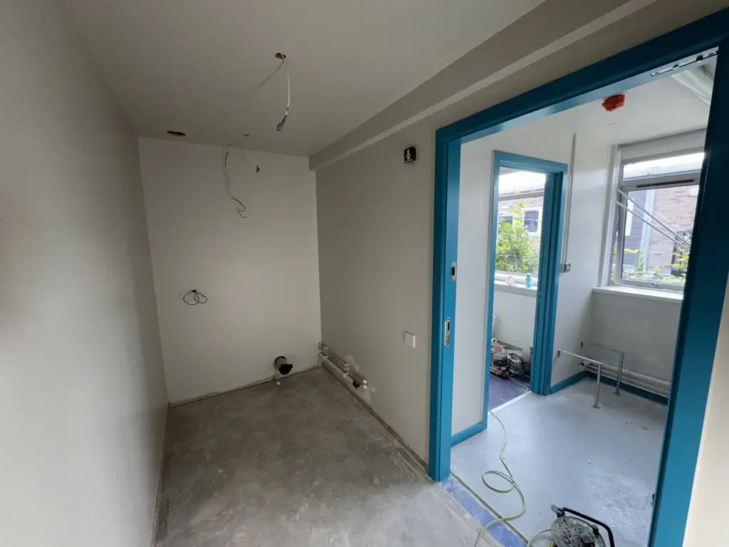 The Hawthorns School washroom during late fit-out with finished walls, teal door linings and services awaiting second fix