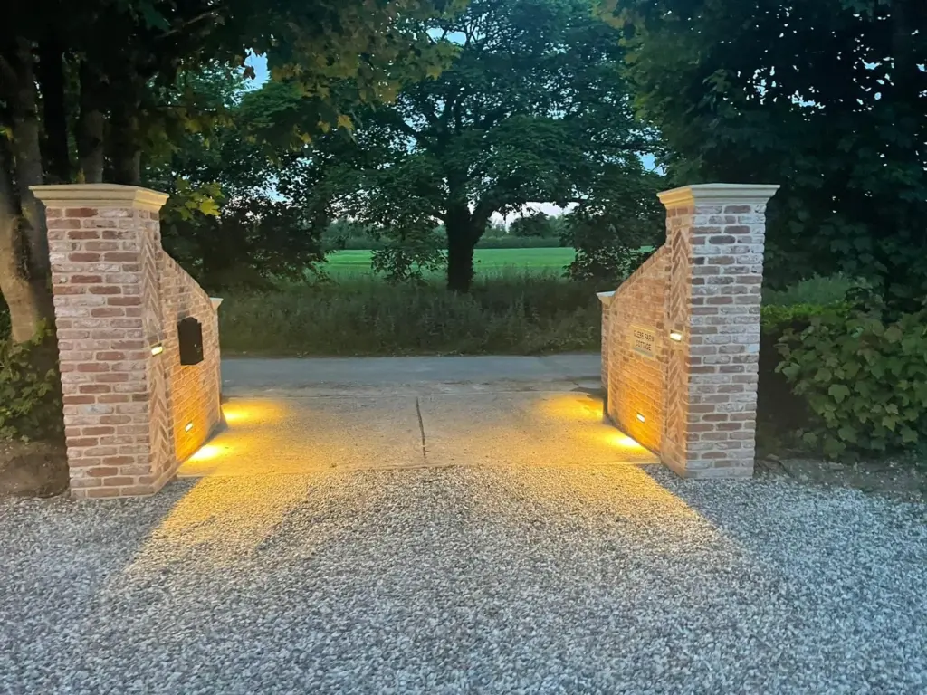 Completed Rivenhall driveway entrance with lit brick piers, stone caps and shingle surface