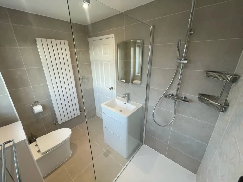 Completed low-threshold walk-in shower in a Tiptree bathroom installation with large grey wall tiles