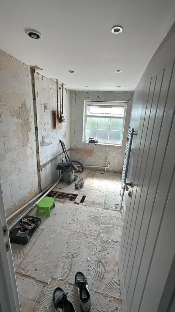 Stripped-back family bathroom during refurbishment in Witham, Essex, with exposed pipework and lifted floorboards