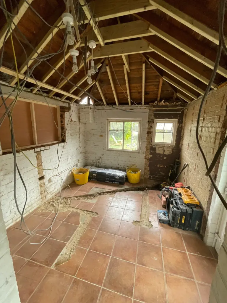 Interior of the rear outbuilding at this Witham home before conversion, with original roof timbers and windows