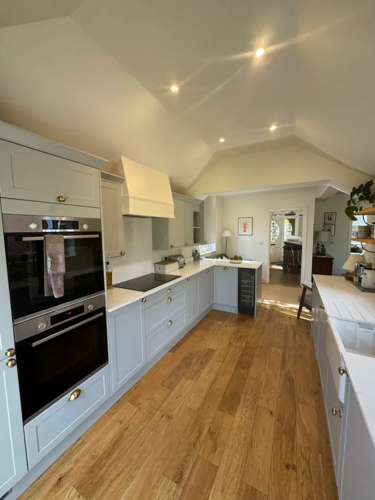 Close view of the finished Benchmarx kitchen in Witham, with integrated ovens and engineered wood flooring