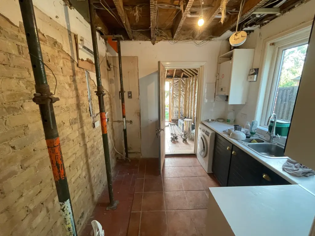 Original galley kitchen in Witham before refurbishment, with exposed ceiling joists and acrow props supporting the structure