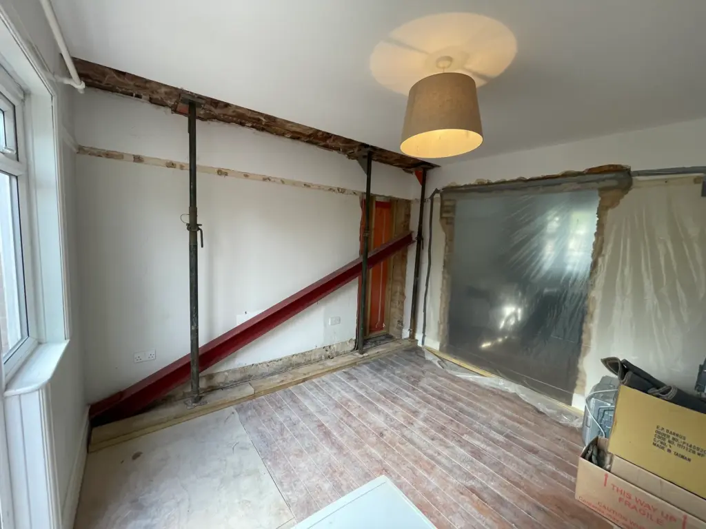 Structural opening mid-build in Witham, with acrow props supporting a new steel beam where the kitchen and outbuilding wall was removed
