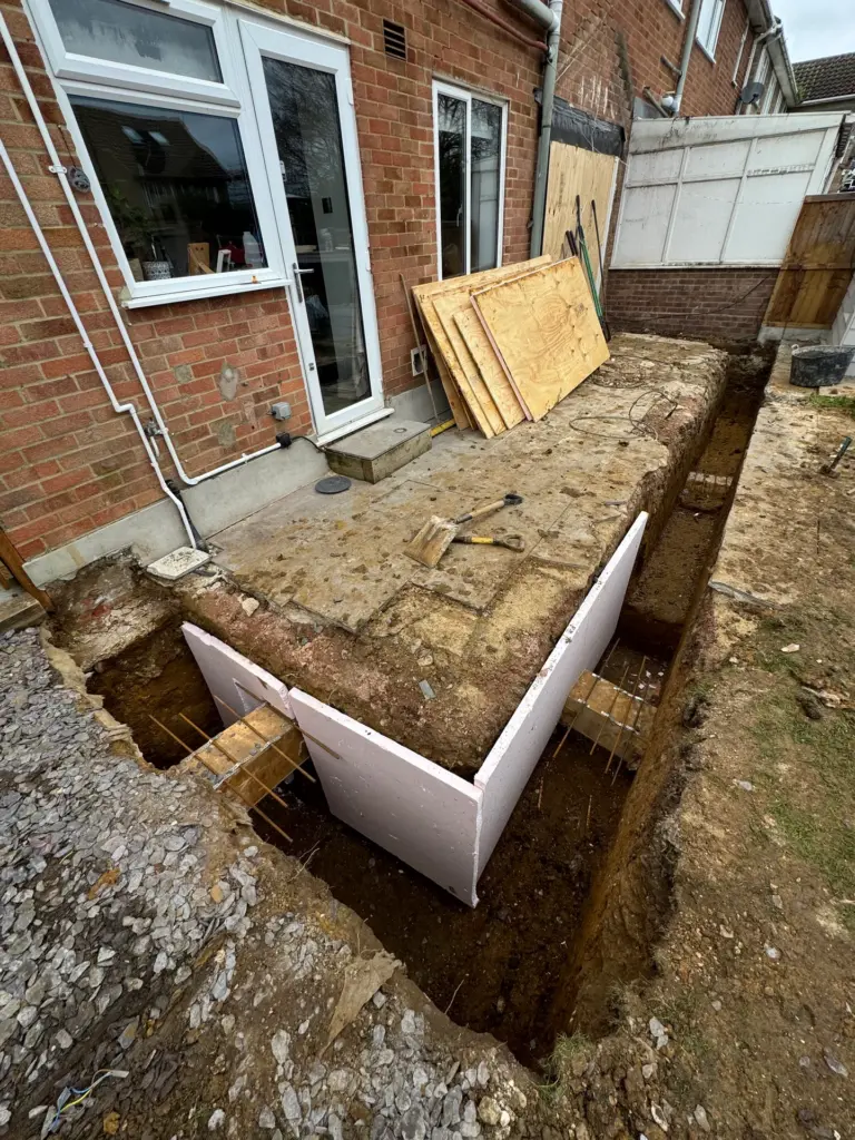 Excavated foundation trench with reinforcement bar for a single storey rear extension in Writtle