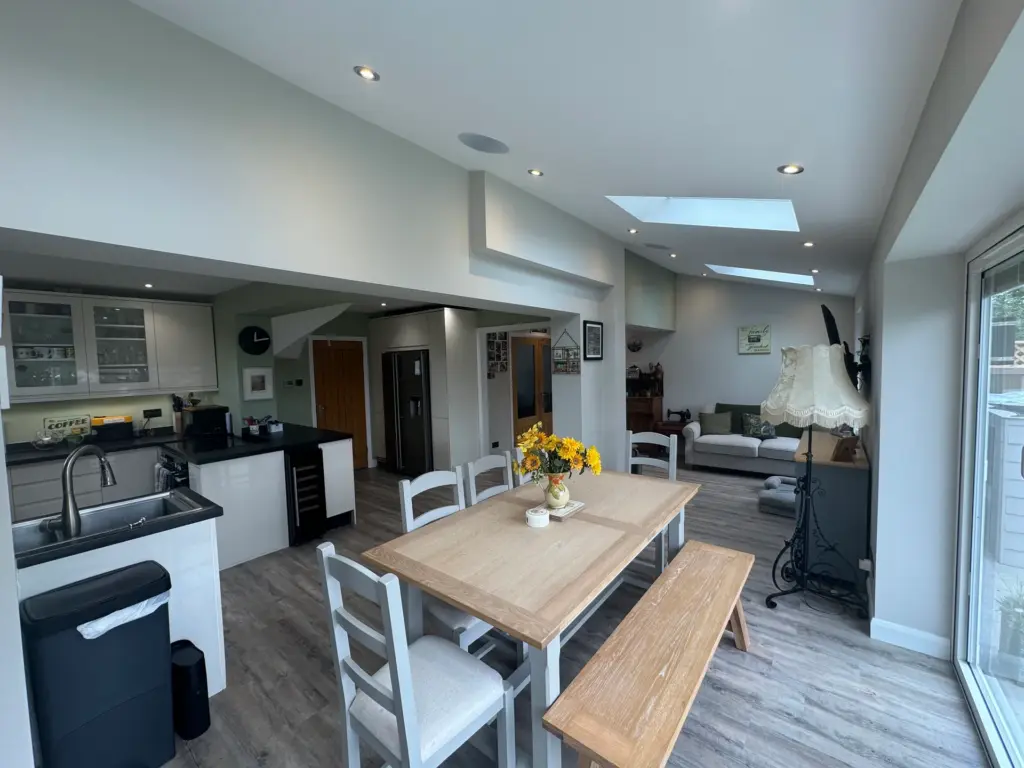 Furnished open-plan kitchen-diner in the Writtle extension, with the dining table, fitted kitchen and roof windows overhead