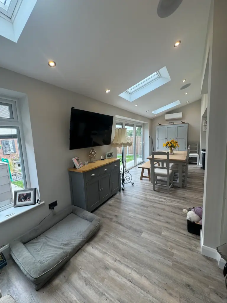 Furnished living and dining space in the completed Writtle extension with roof windows and wood-effect flooring