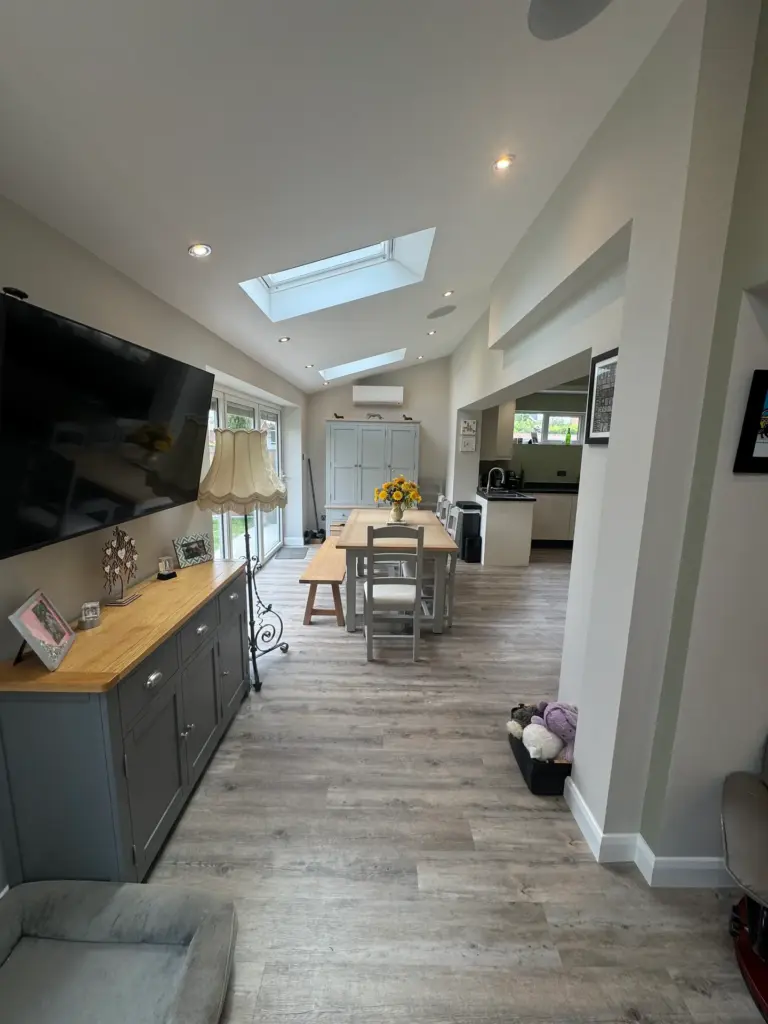 Living end of the furnished Writtle extension with wall-mounted TV, sideboard and dining table beyond