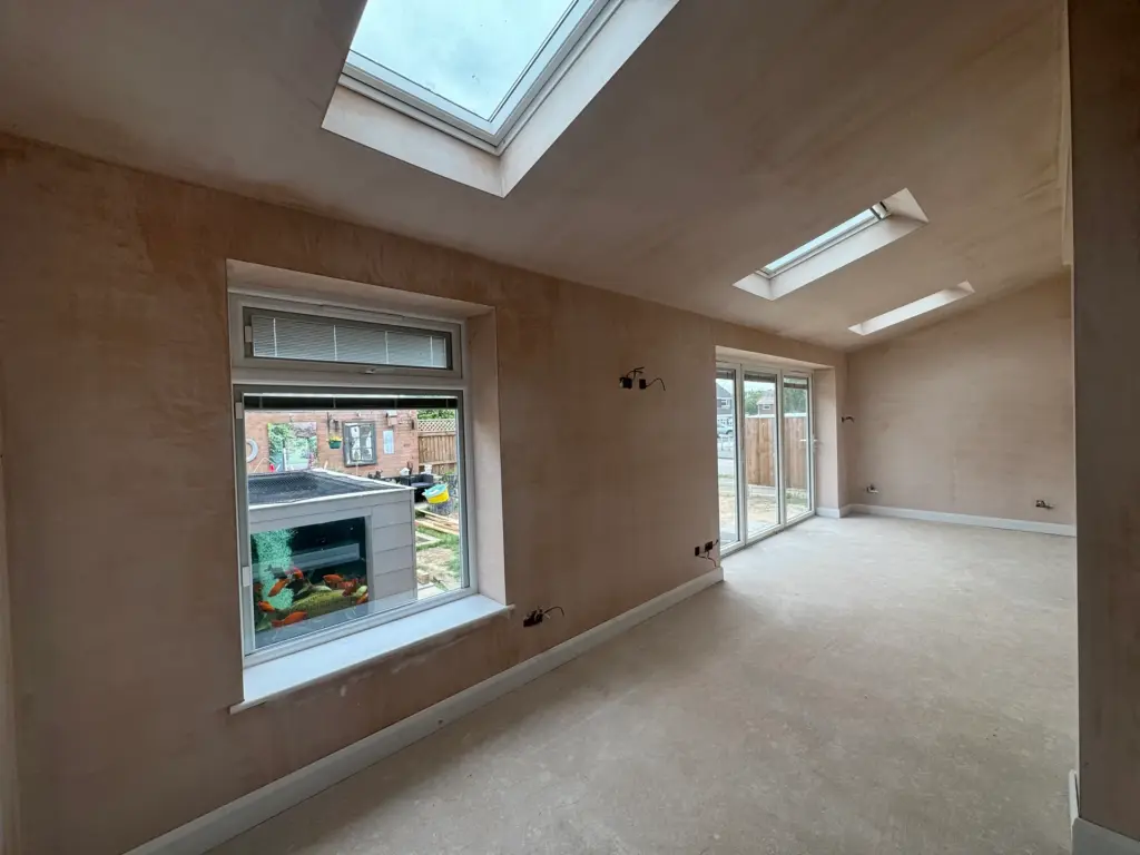 Plastered living space in the Writtle extension ahead of flooring, with full-height doors to the garden